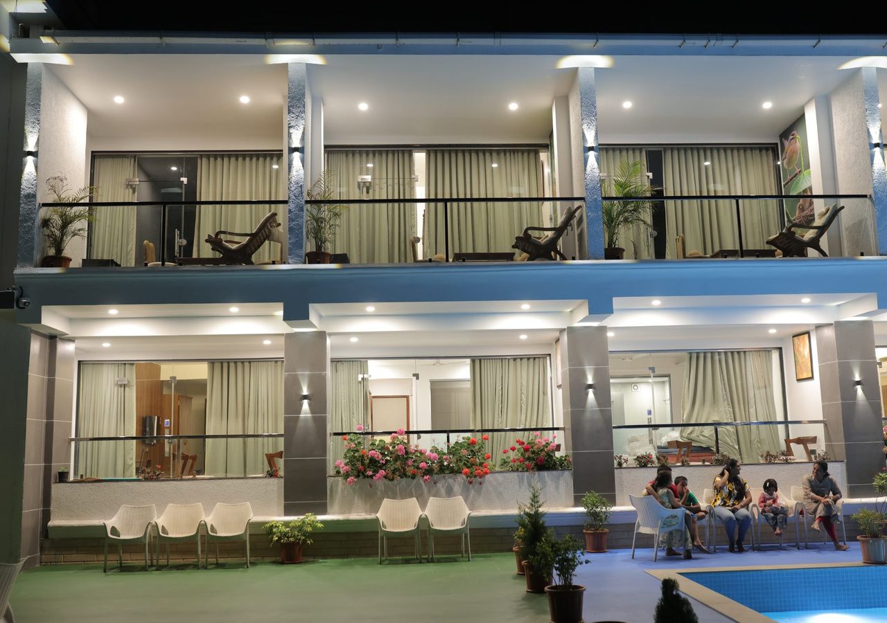 A hotel lobby with a seating area, a pool, and a balcony with chairs.