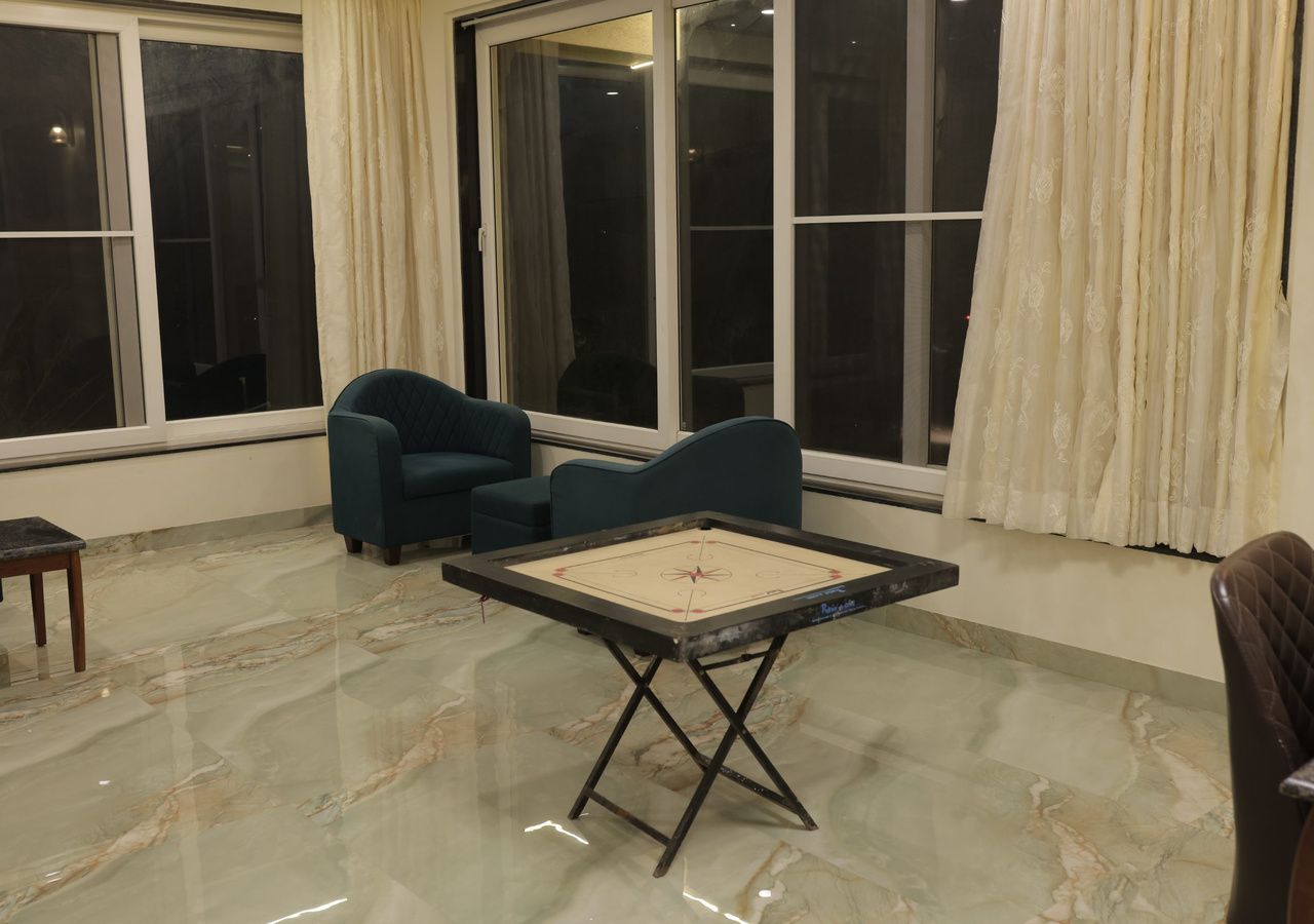 Una habitación con un ventanal grande, una mesa con un juego y dos sillas.