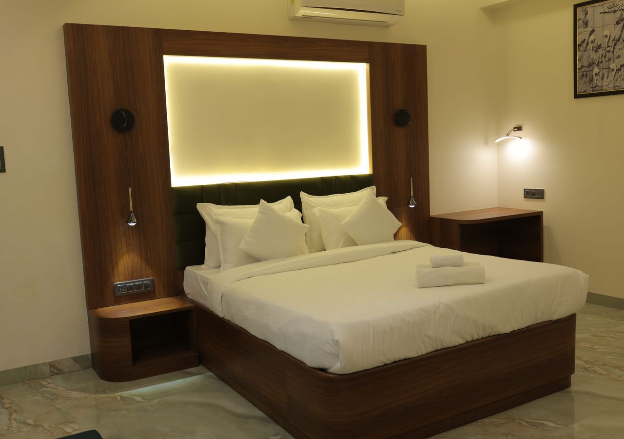 Habitación de hotel moderna con una cama grande, cabecero de madera, mesitas de noche y aire acondicionado de pared.