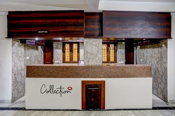Bancada de recepção com tampo de mármore e porta de madeira com a inscrição 'Collection'.