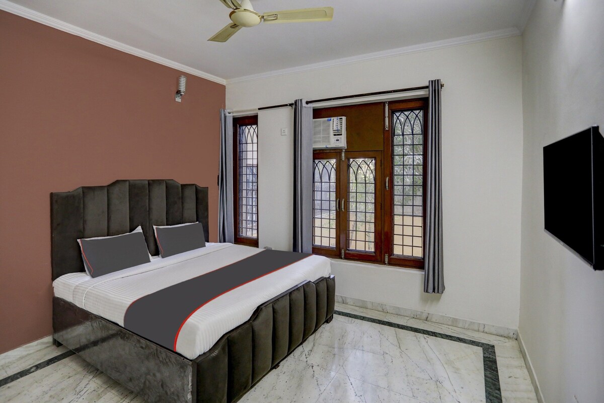 Un dormitorio con cama, ventilador de techo, ventana con vistas y televisor instalado en la pared.