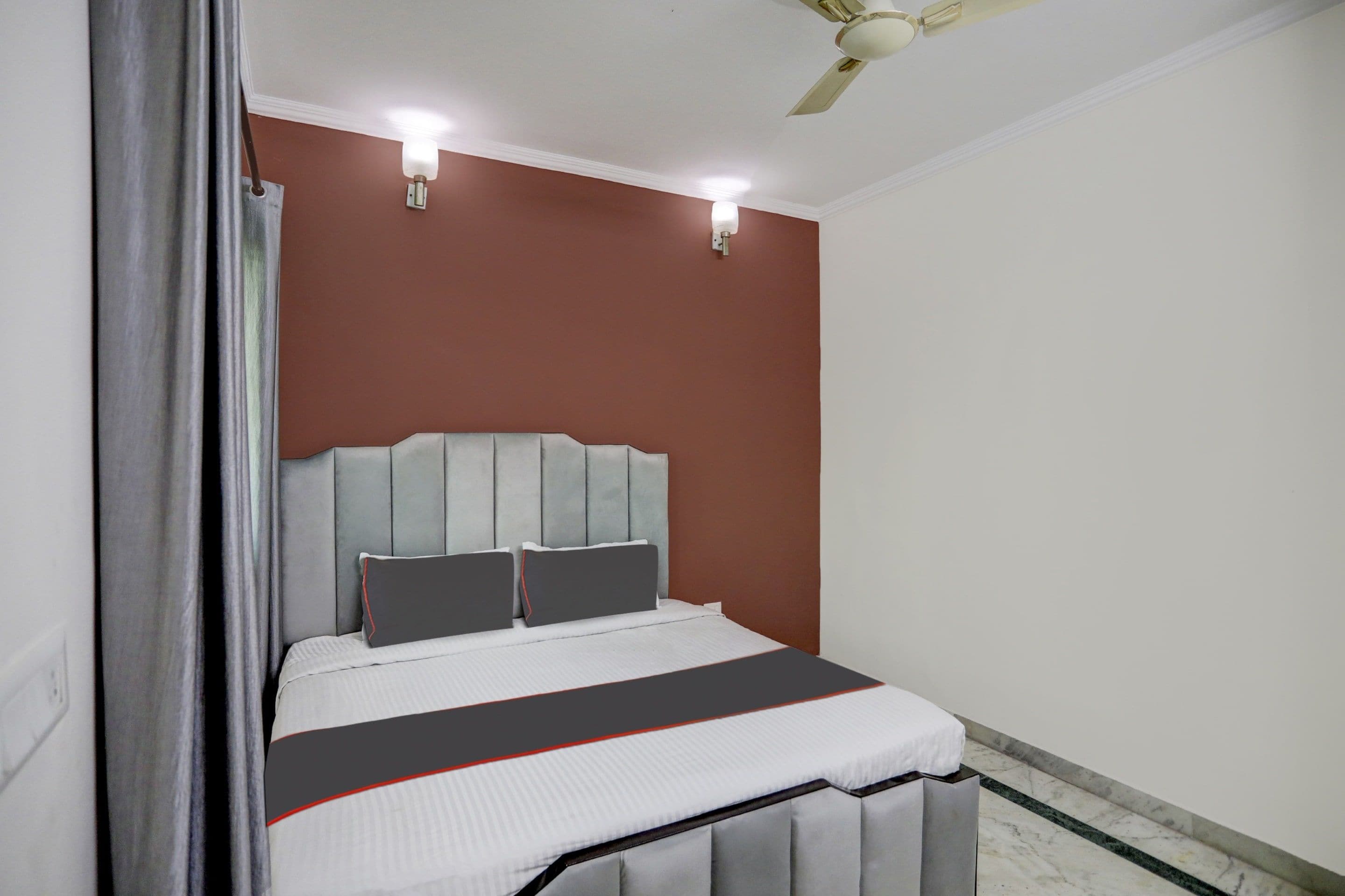 A bedroom with a bed, two wall-mounted lights, a ceiling fan, and a marble floor.