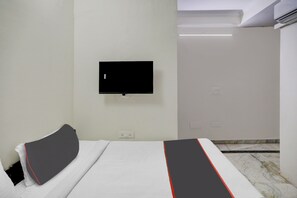 Habitación de hotel con cama, televisor de pantalla plana montado en la pared y piso de mármol.