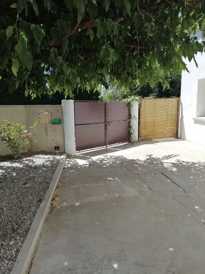 Ein verschlossenes Tor mit einem Betonweg, einem Metallgitter und einem Holzzaun.