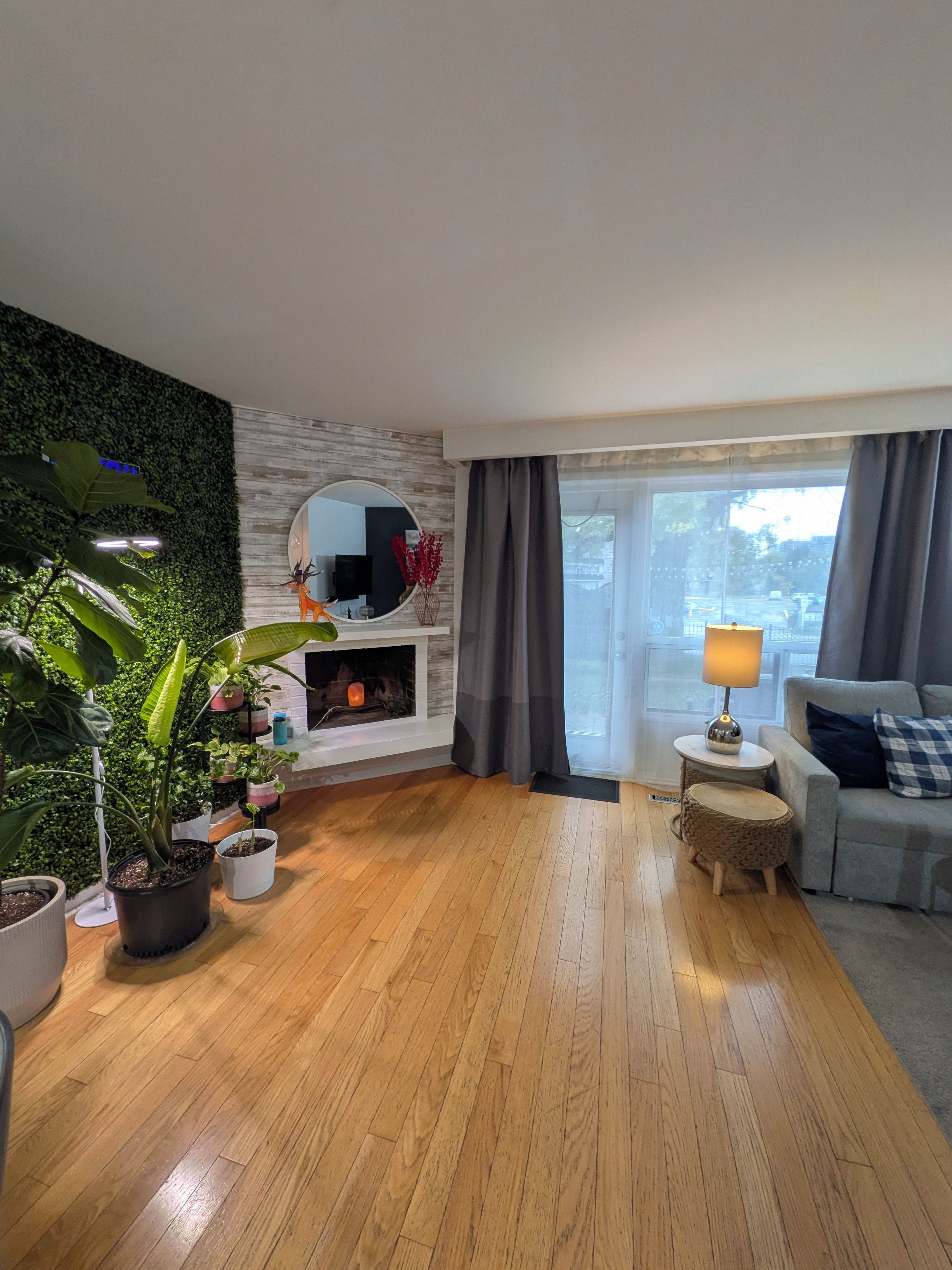 Een moderne woonkamer met een open haard, een bank, een salontafel en een groot raam met gordijnen.