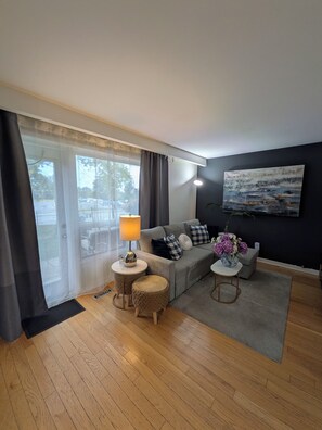 A modern living room with a grey sofa, a round coffee table, a lamp, and a painting on the wall. - Room #3 - Queen Size Bedroom in Shared Townhouse (Toronto)