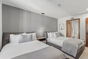 A hotel room with two beds, a wooden door, and a bathroom visible through the doorway. - Private Ritz-Carlton Residence by InvitedHome | Ski Shuttle, Ski Valet, Hot Tub (Vail)