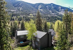 A cabin with a metal roof, surrounded by dense forest and mountains. - 5BR Vail Mountain Home | Hot Tub, Sleeps 16 (Vail)