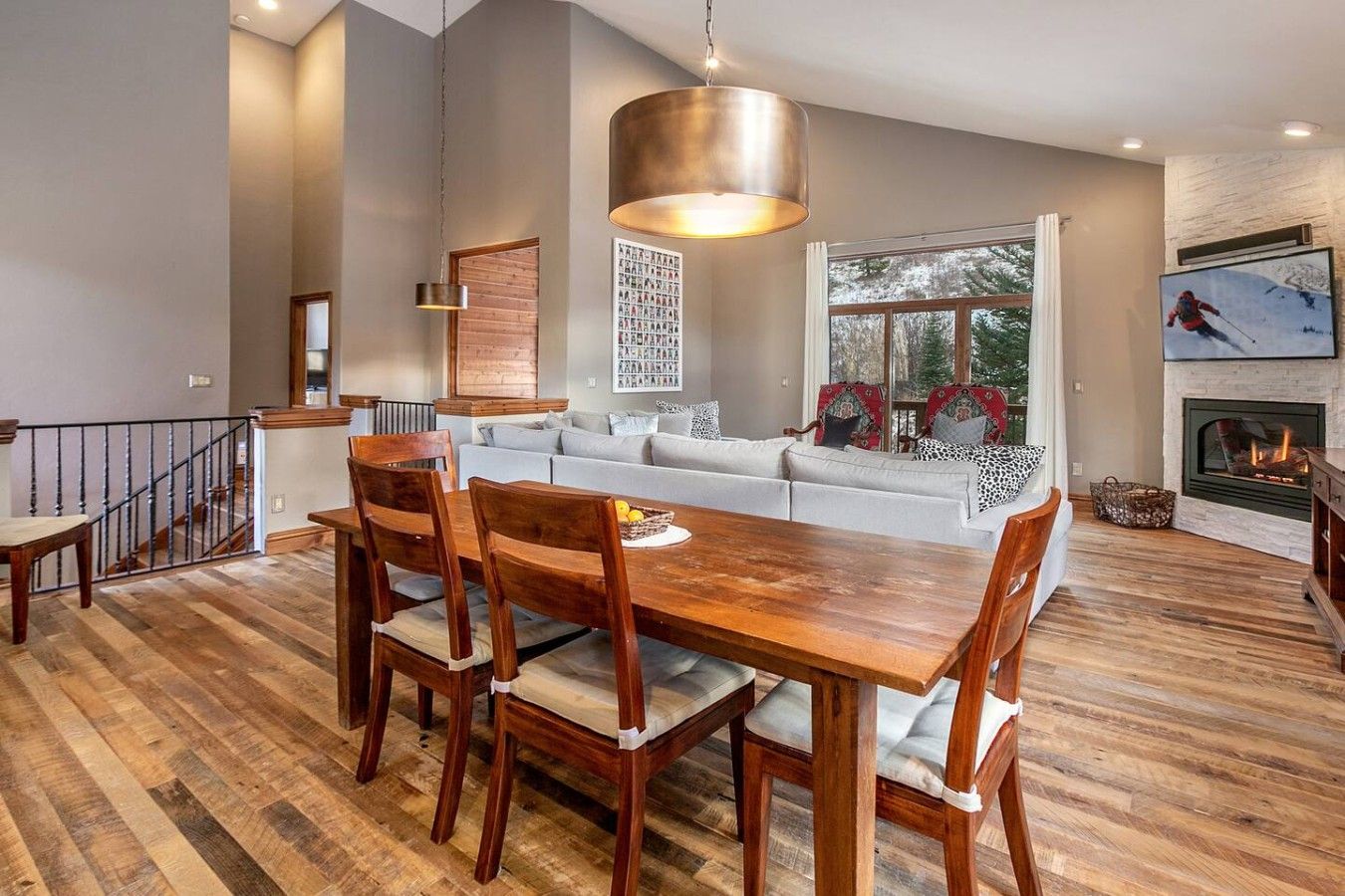 A modern living room with a dining area, a fireplace, and a large window with a view.