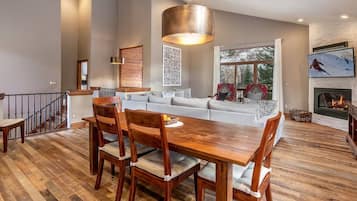 A modern living room with a dining area, a fireplace, and a large window with a view.