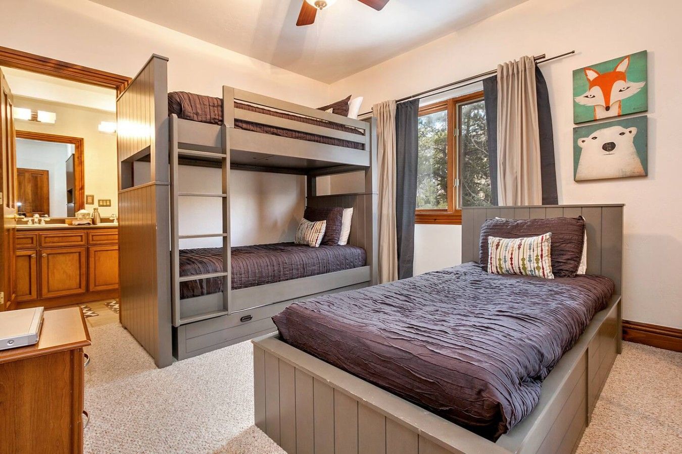 A bedroom with bunk beds, a large window with curtains, and a mirror.