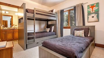 A bedroom with bunk beds, a large window with curtains, and a mirror.