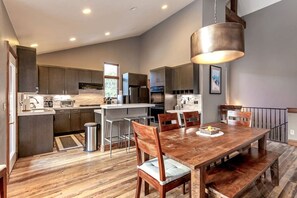 Una cocina moderna con armarios oscuros, una isla central y un comedor con sillas de madera y una mesa.