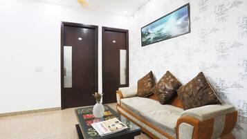 A room with a sofa, a coffee table with magazines, a decorative vase, and a framed picture on the wall.