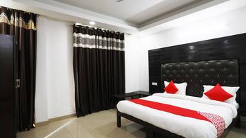 A hotel room with a bed, a nightstand, a ceiling fan, and a window with curtains.