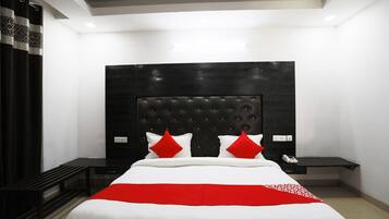 A modern bedroom with a large bed, a dark headboard, and a red accent pillow.