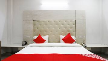 A hotel room with a large bed, two bedside tables, a red and white bedspread, and a modern headboard.