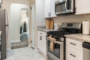 A modern kitchen with stainless steel appliances, a granite countertop, and white cabinetry.