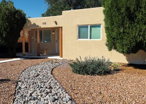 A modern building with a beige facade, a numbered address, and a gravel pathway leading to the entrance. - 3-bedroom house in tranquil Albuquerque Home away from Home (Albuquerque)