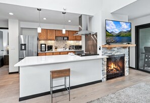 A modern kitchen with a large island, stainless steel appliances, and a fireplace. - Spacious Vail Condo, steps to Free Shuttle | BW534 (Vail)