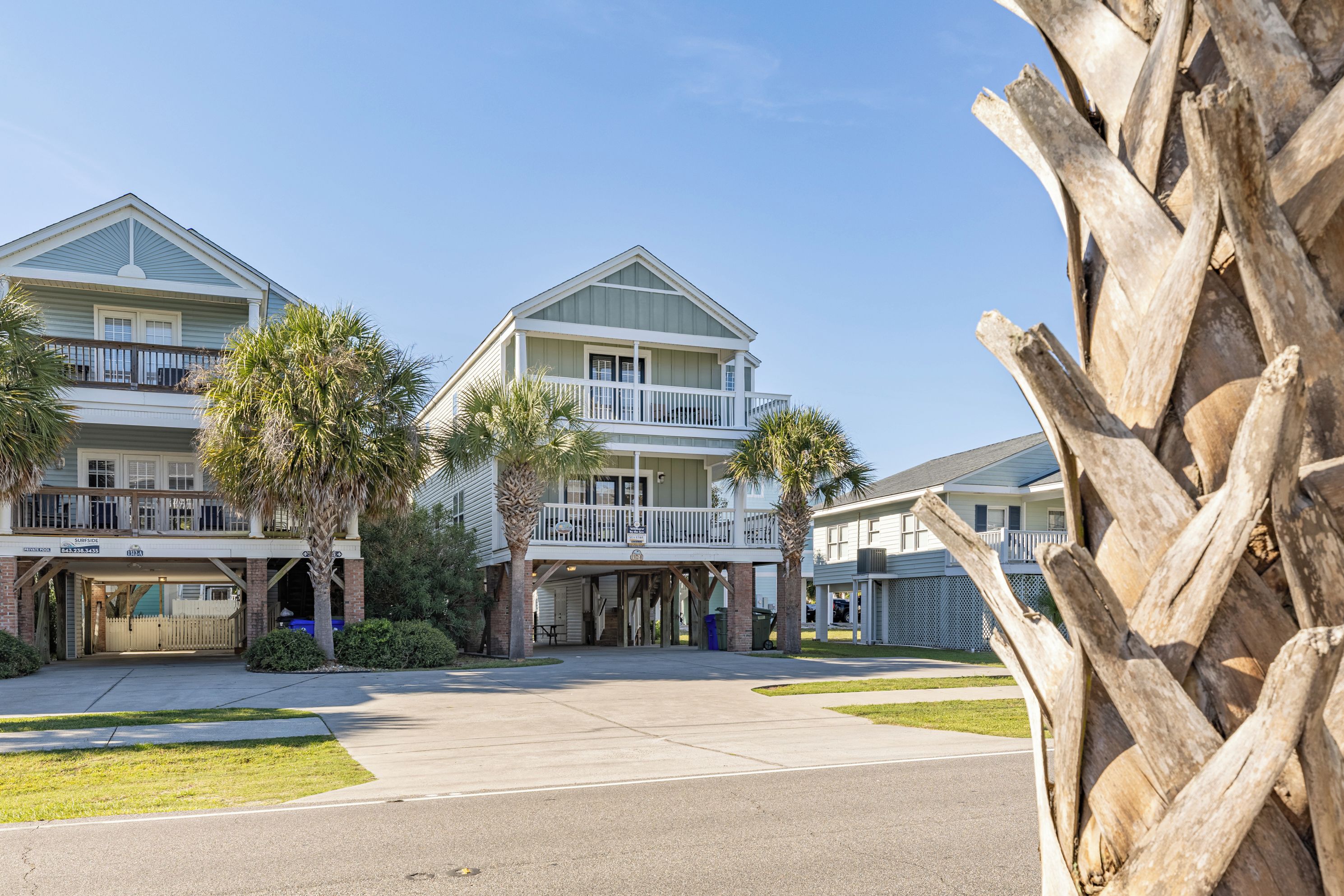 A beachfront hotel with multiple-story buildings, balconies, and palm trees.