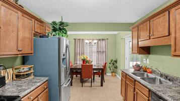 A kitchen with wooden cabinets, a blue refrigerator, a dining table with chairs, and a chandelier.