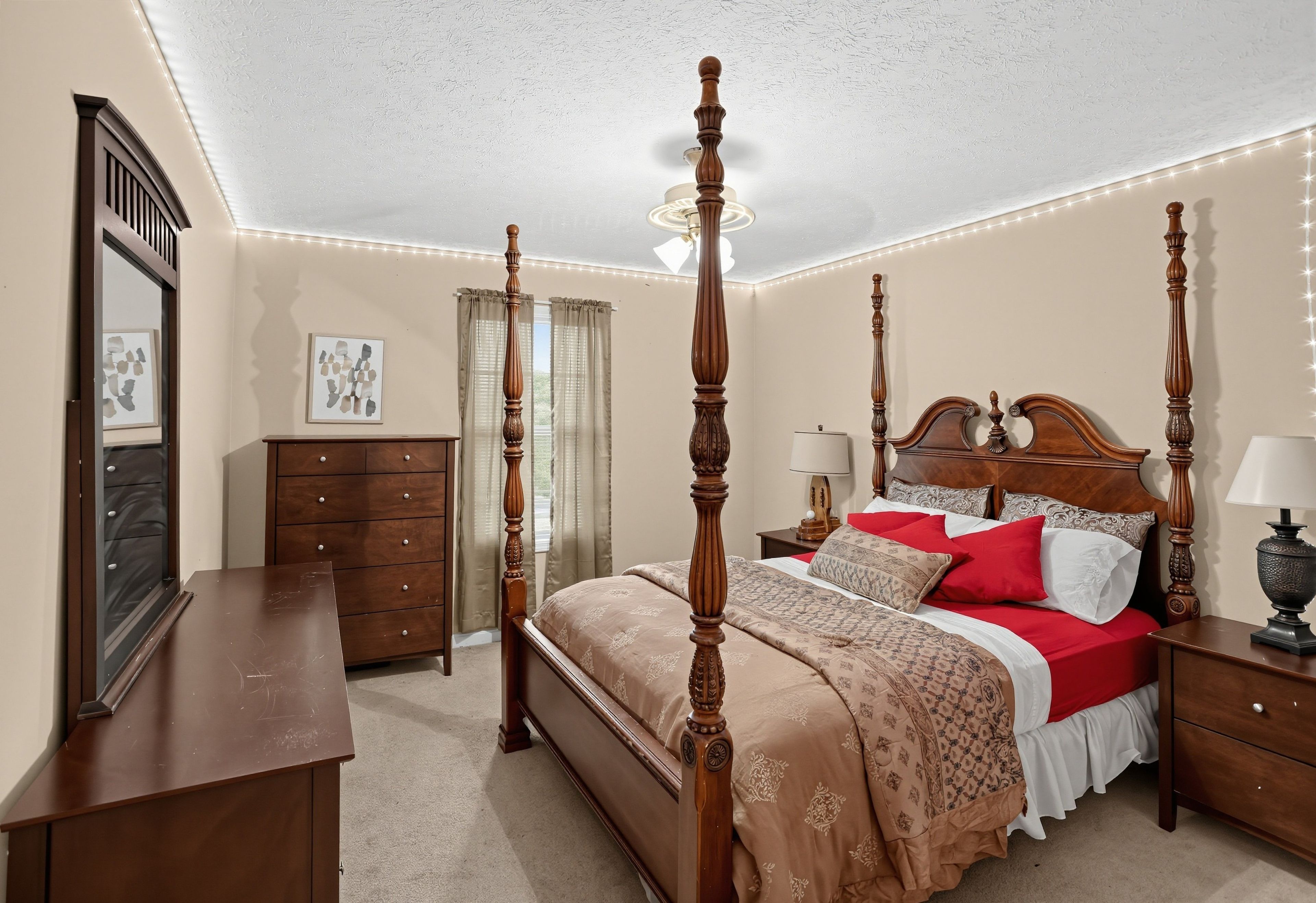 A four-poster bed with a wooden headboard, a bedside table with a lamp, a dresser, and a mirror on the wall.