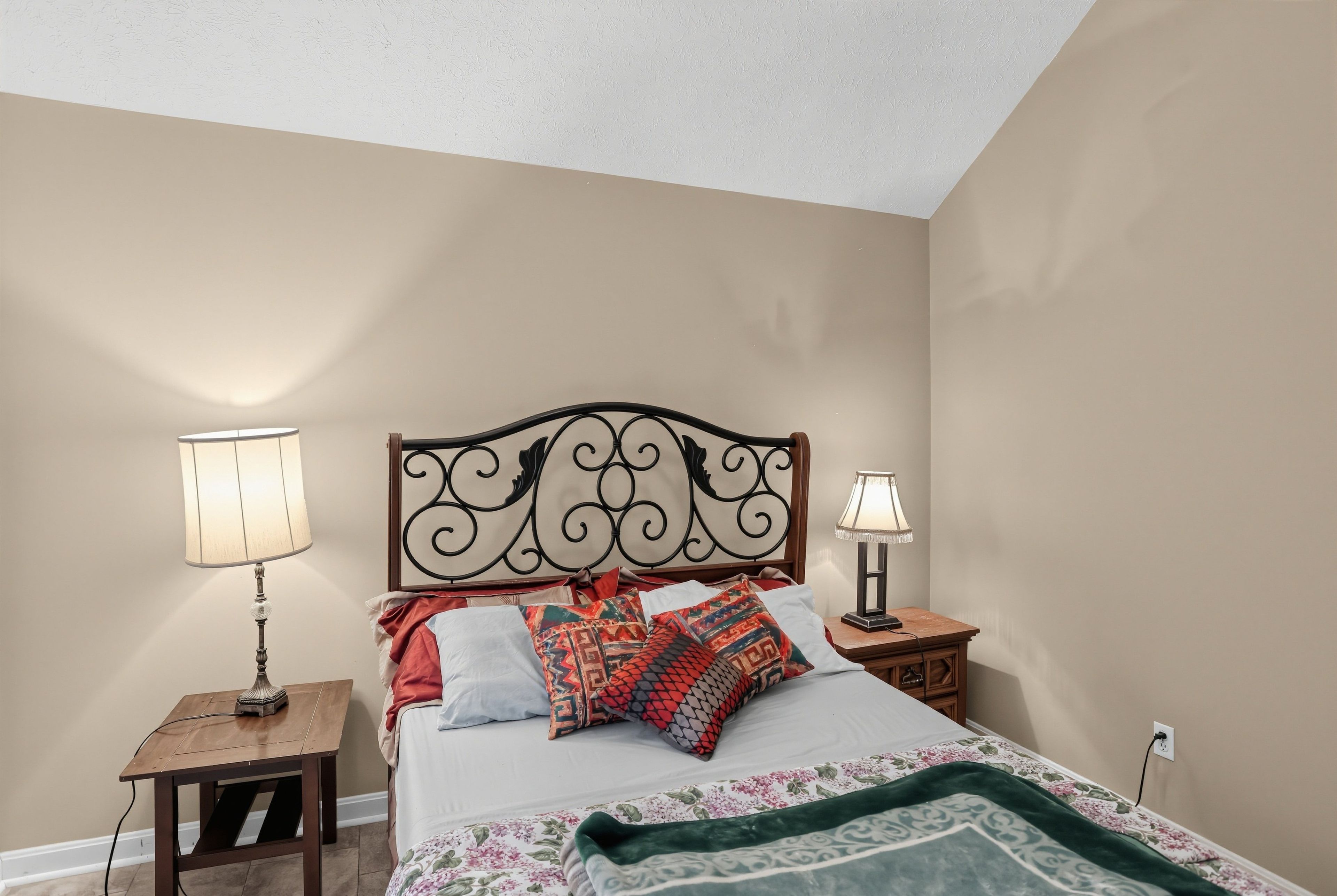A bedroom with a bed, two bedside tables, and two lamps.