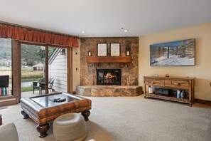 A living room with a stone fireplace, a glass coffee table, and a painting on the wall. - 2br Deer Valley Retreat Hot Tub & Fireplace 2 Bedroom Condo (Park City)