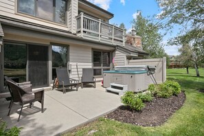 A two-story house with a covered patio area featuring outdoor furniture and a hot tub. - 2br Deer Valley Retreat Hot Tub & Fireplace 2 Bedroom Condo (Park City)