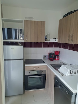 A compact kitchen with a refrigerator, microwave, oven, and a coffee maker. - Air-conditioned chalet for 6–8 people in a vacation resort (Parentis-en-Born)