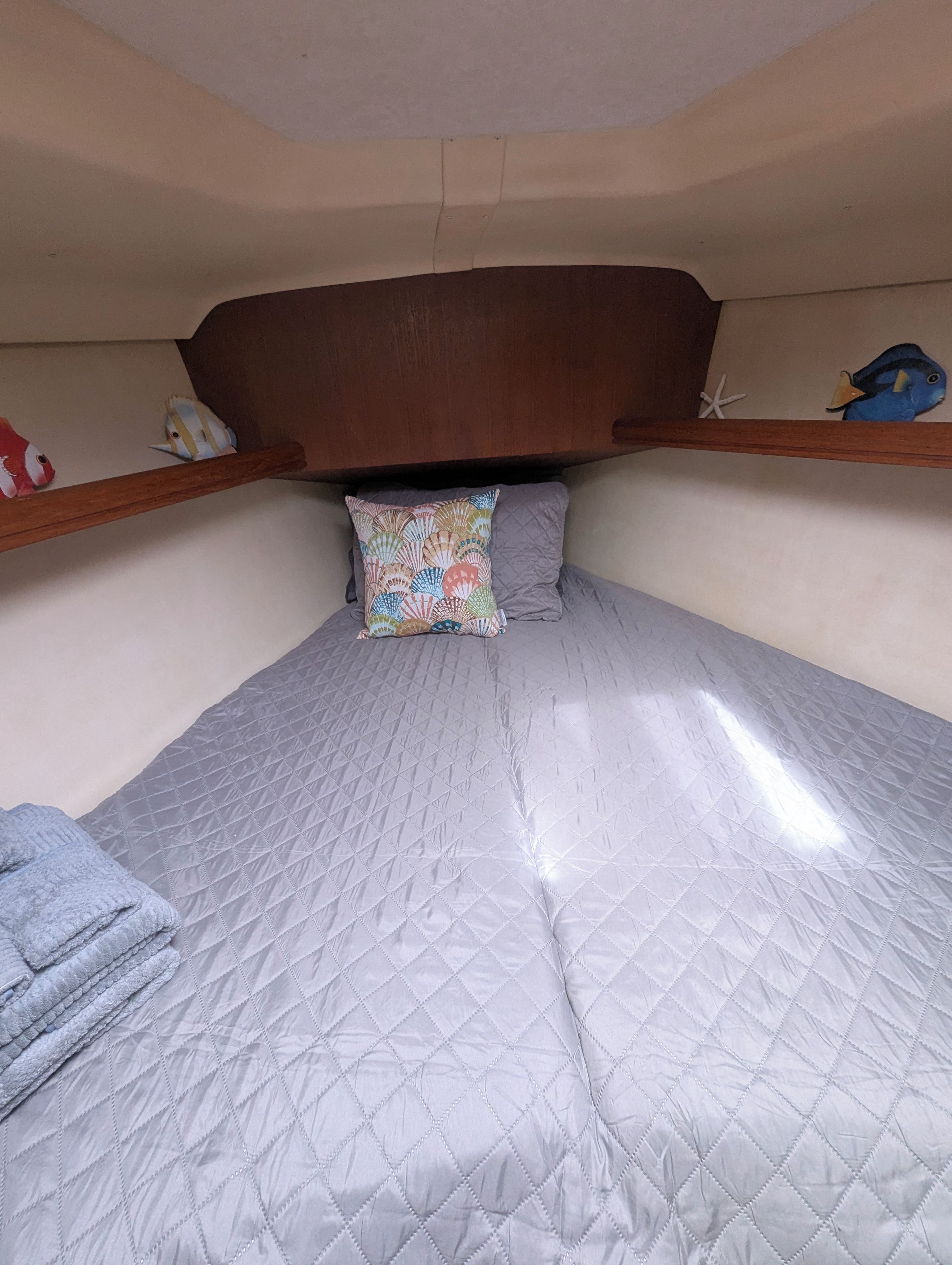 Een stapelbed met een gewatteerde matras, een kussen met een schelpenprint en een houten hoofdbord.
