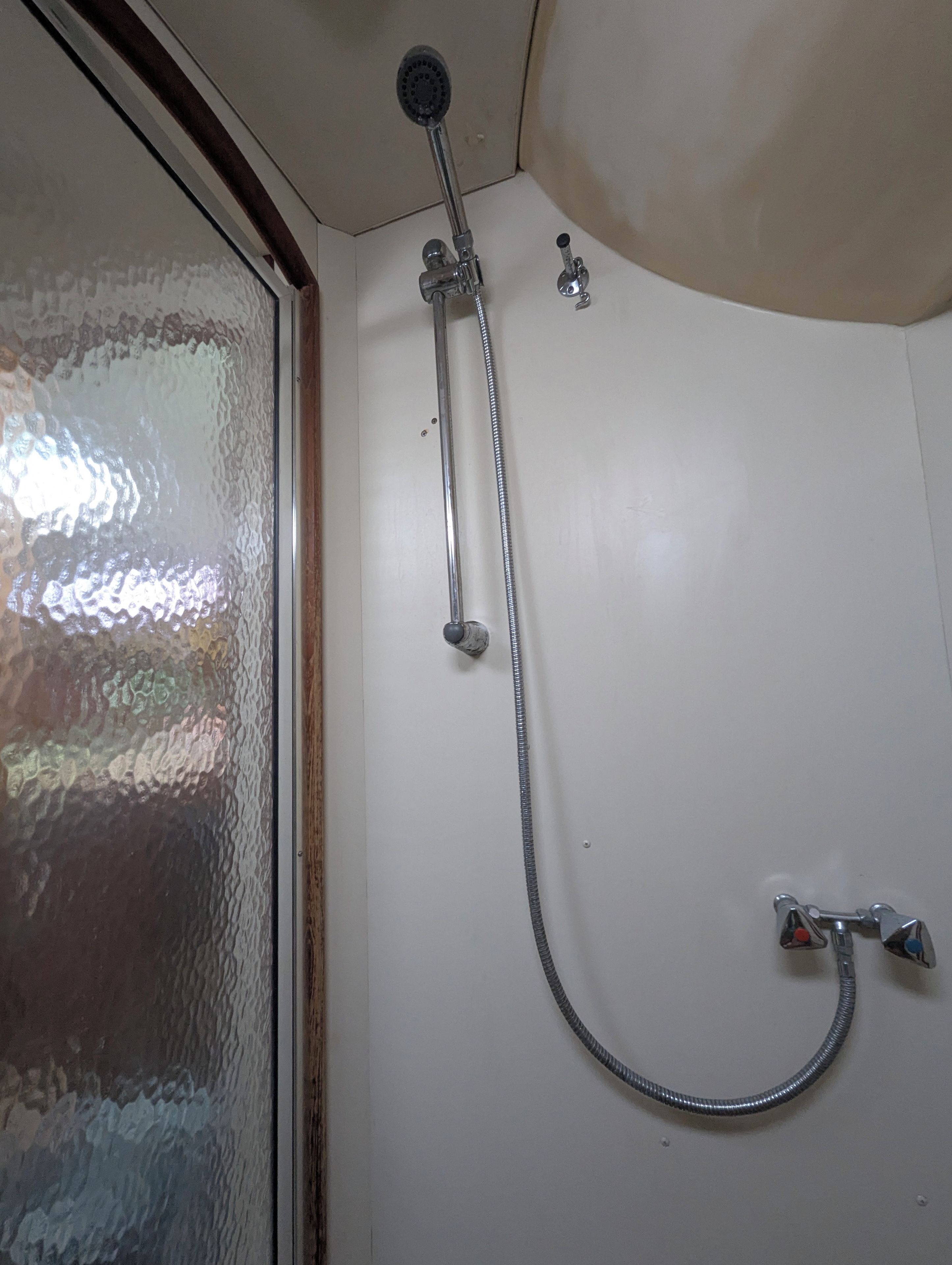 Une douche équipée d’un pommeau de douche à main et d’un flexible.