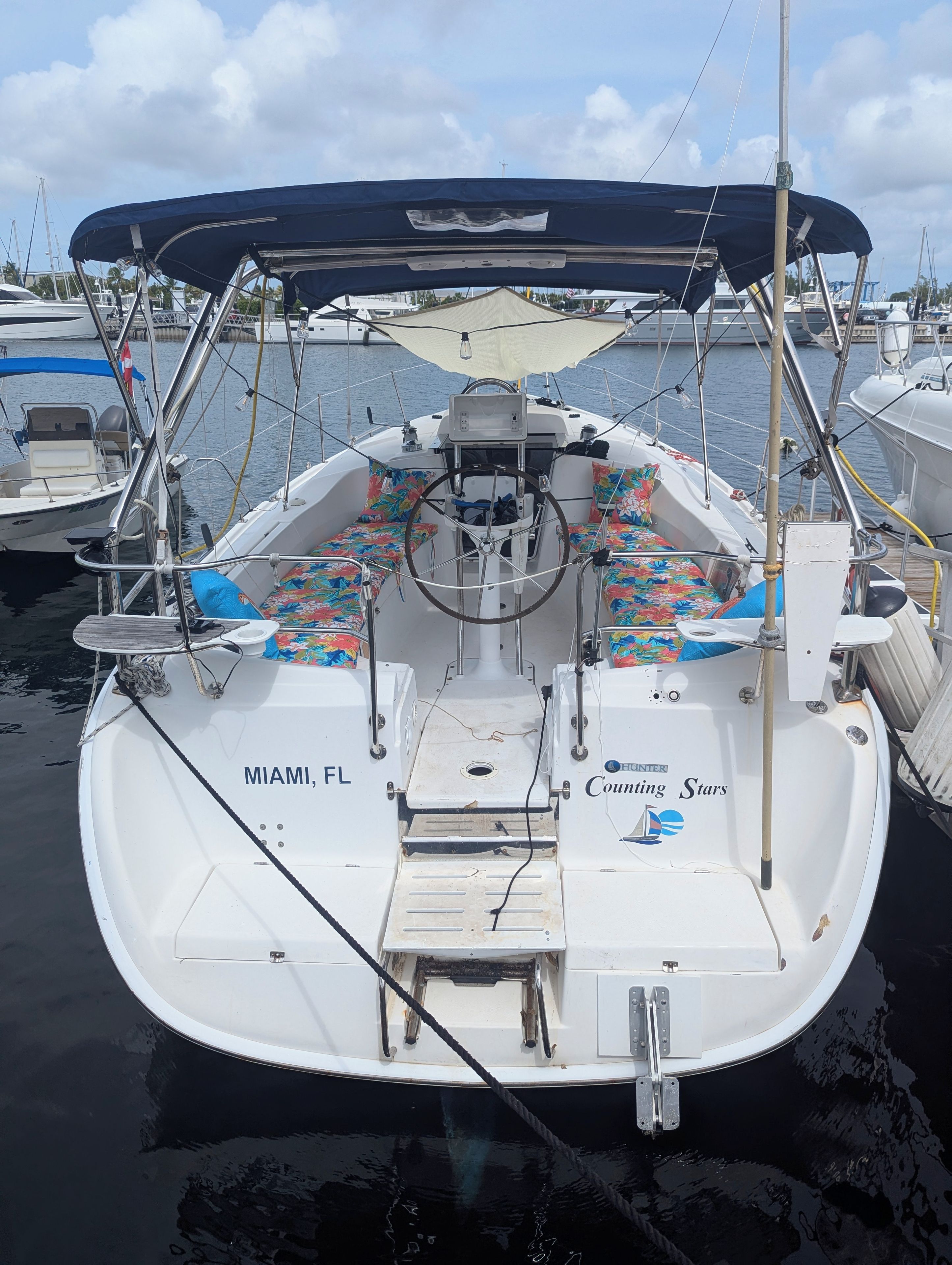 A boat with a covered seating area, a steering wheel, and the text 'MIAMI, FL' and 'Hunting Stars' on the side.
