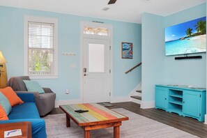 Ein Wohnzimmer mit einer Couch, einem Couchtisch, einem Fernseher und einem Gemälde.