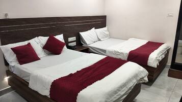 Een hotelkamer met twee bedden, elk met witte beddengoed en rode accenten, en een donker houten hoofdbord.