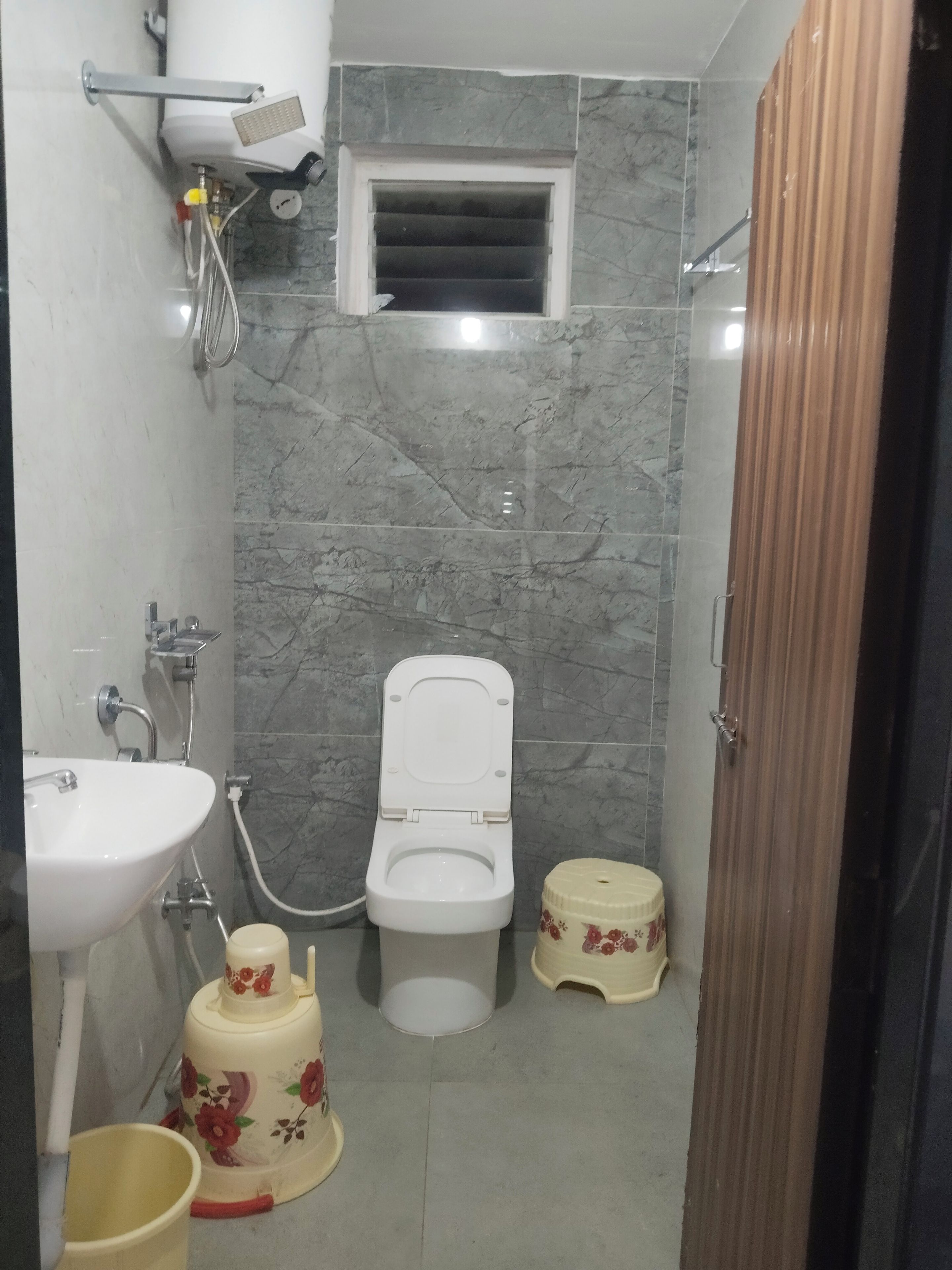 Un baño con inodoro, lavamanos y un ventanal pequeño.