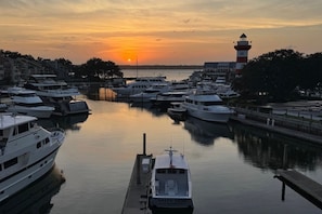 A marina with multiple boats docked, a lighthouse in the background, and a sunset. - One bedroom oasis in the heart of sea pines with harbour and lighthouse views (Hilton Head Island)