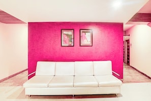 A white sofa in a hallway with a bright pink wall and two framed pictures. - Townhouse TIPSYY INN 023 (Jaipur)