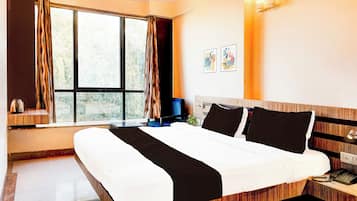 Una habitación de hotel con una cama grande, una mesita de noche con teléfono y una ventana con cortinas.