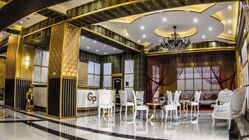 A luxurious interior with a grand chandelier, elegant seating, and a polished marble floor.