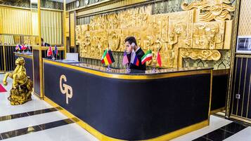 Una mesa de recepción con un logotipo 'GP', varias banderas nacionales y una pared decorativa dorada.