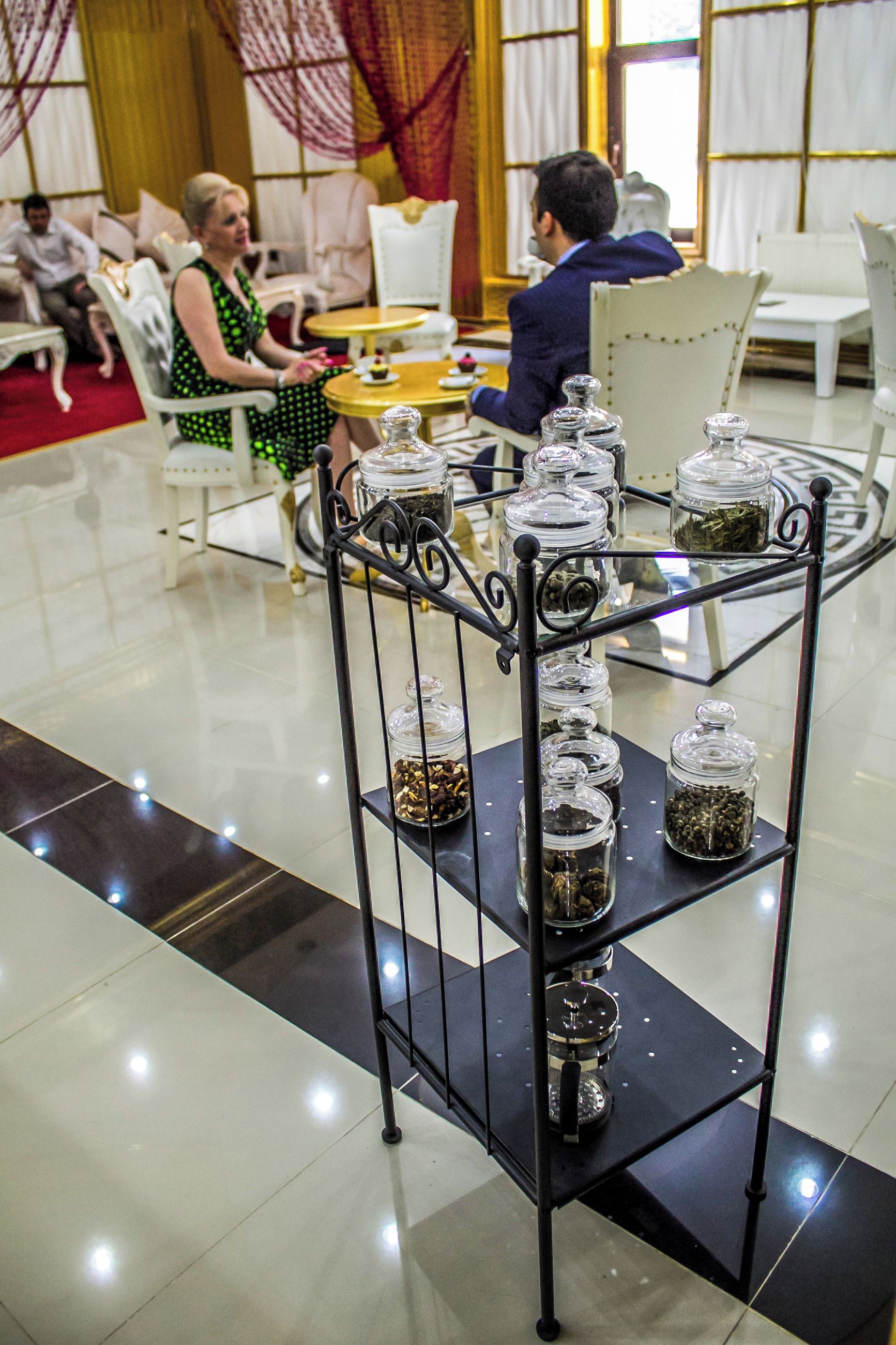 Uma sala de jantar com mesa redonda, cadeiras e um suporte de metal com recipientes de vidro.