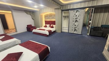 A hotel room with two beds, a sitting area, a wardrobe, and a mirror.