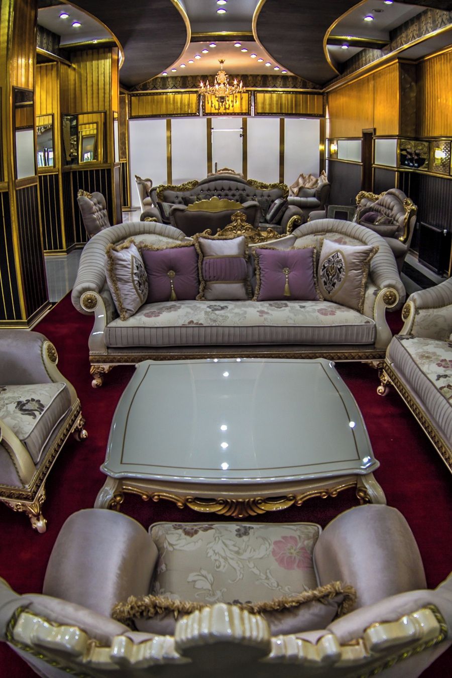 Un salón lujoso con muebles ornamentados, una araña y un ventanal grande.