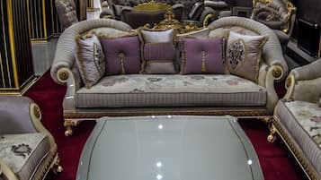 Un salón lujoso con muebles ornamentados, una araña y un ventanal grande.