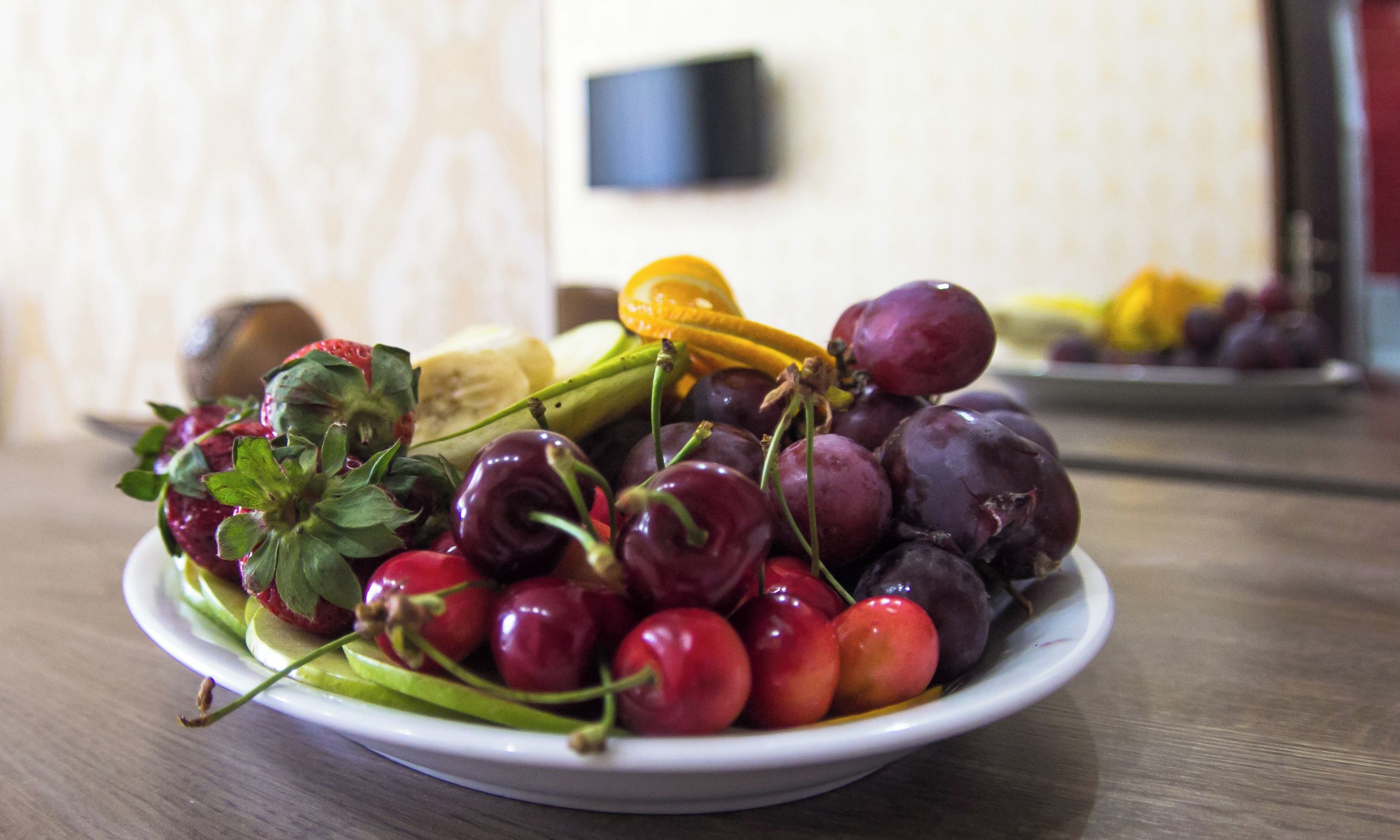 A plate of assorted fruits including strawberries, cherries, grapes, and an orange slice.