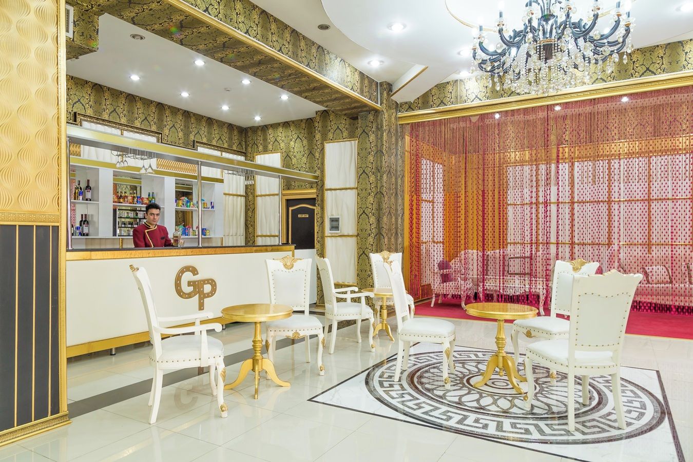 Een luxueuze lobby met een bar, decoratie in wit en goud, en een patroon vloer.