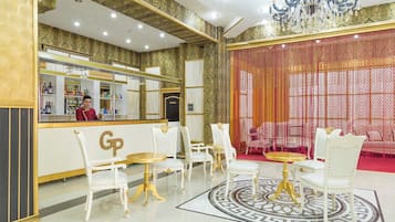 A luxurious lobby with a bar area, white and gold decor, and a patterned floor.