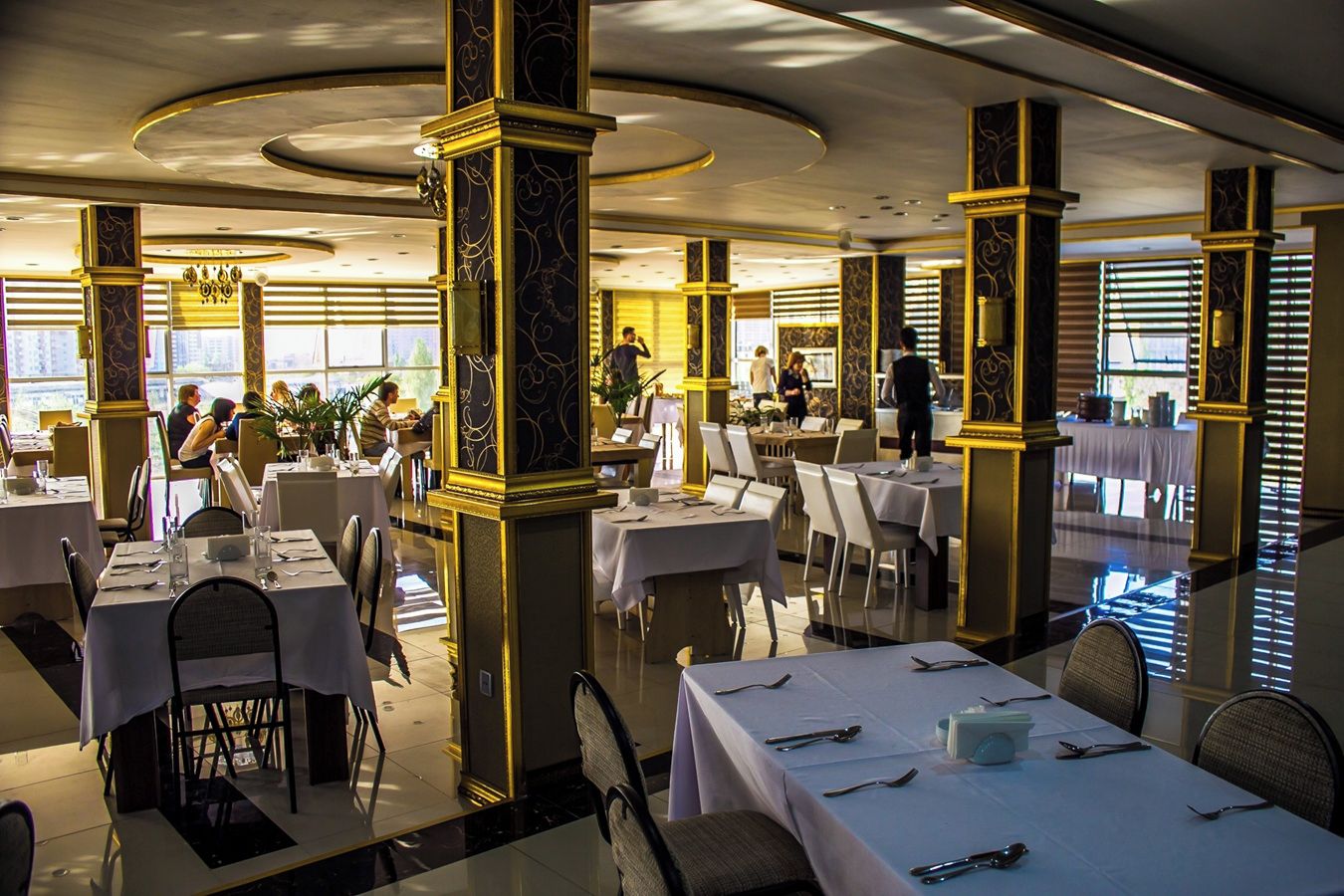 Un restaurant avec des tables rondes, des chaises et un serveur.